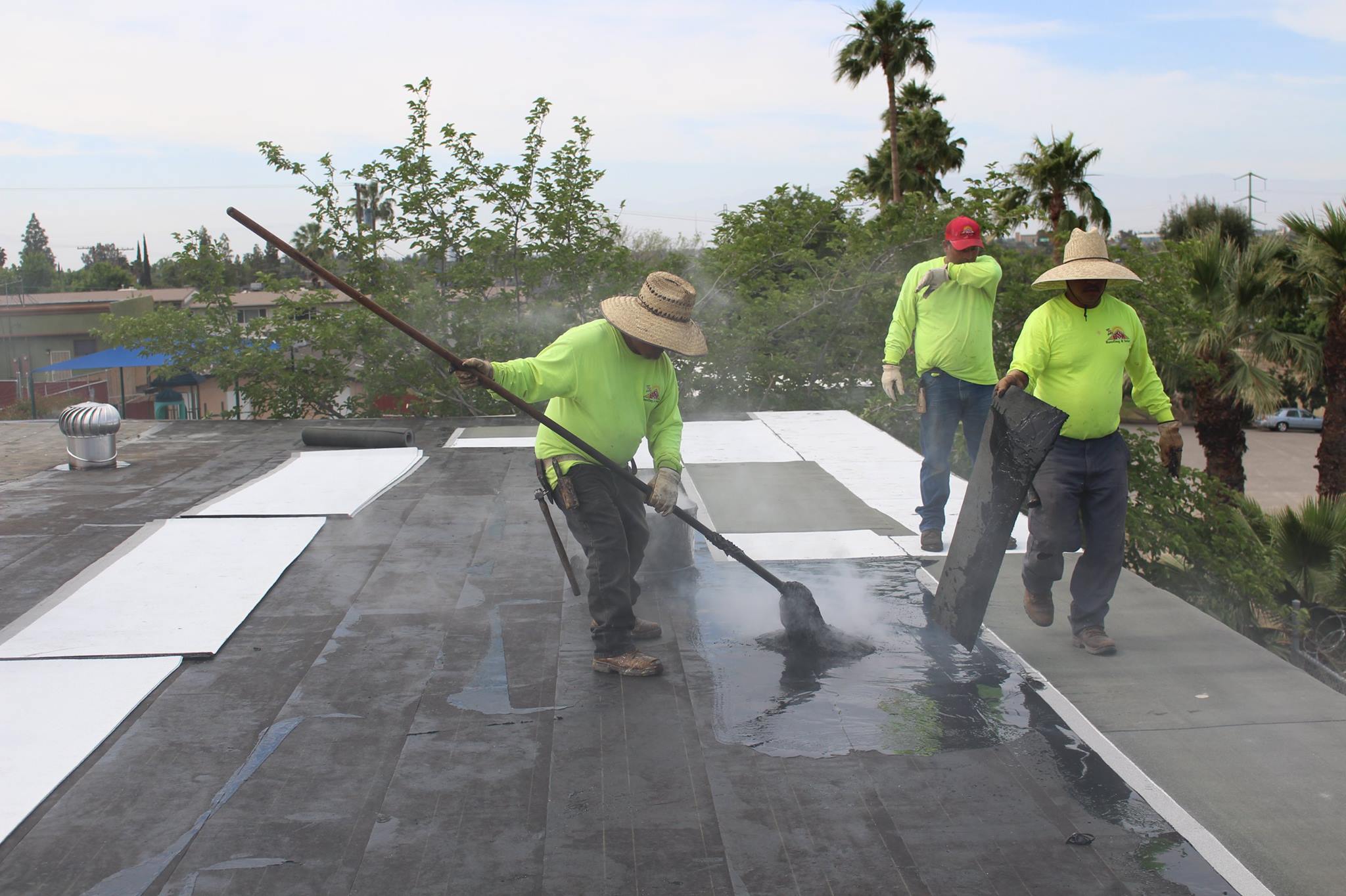 BSW roofers mopping hot asphalt across a flat roof