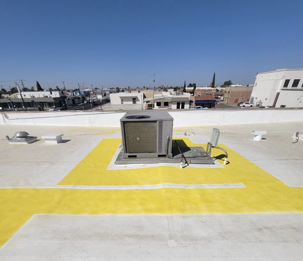 White cool roof with yellow service walkways around an HVAC unit