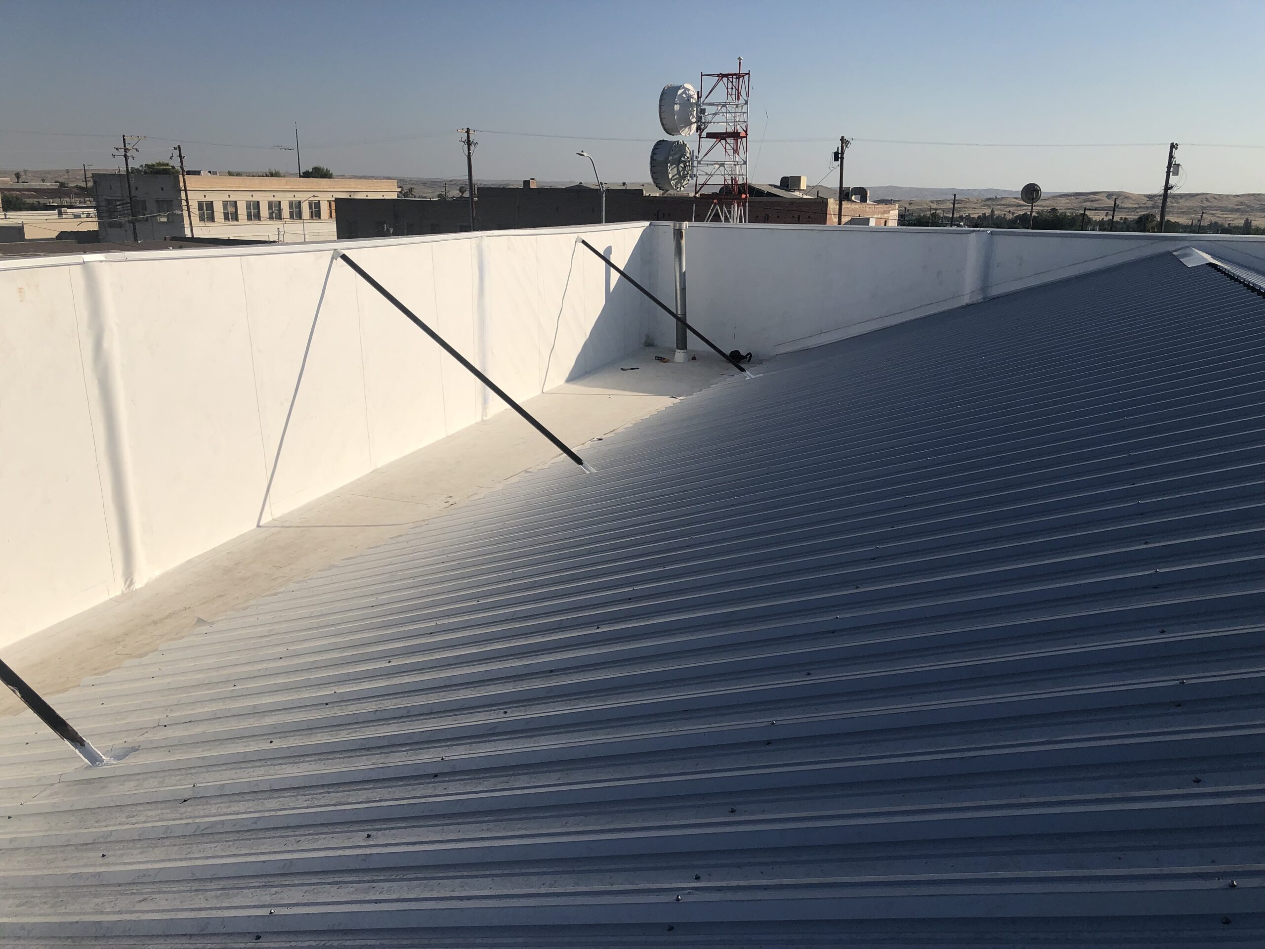 Restored standing-seam metal roof and white parapet walls
