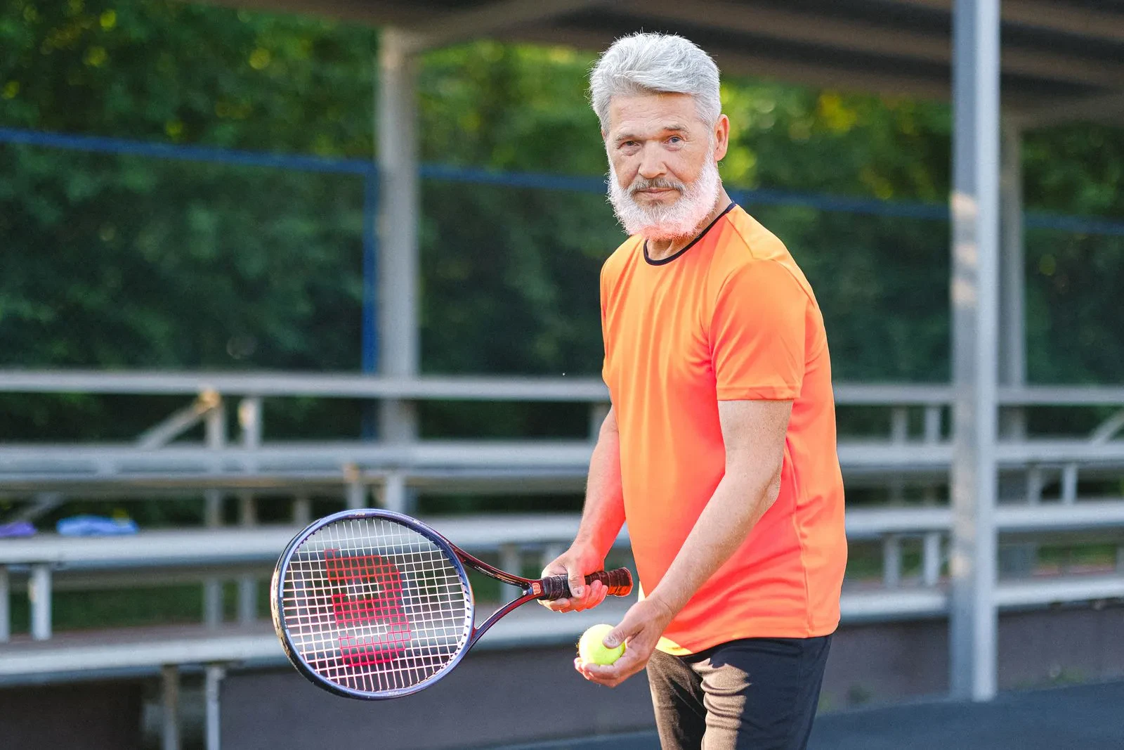 Senior man serving on an outdoor tennis court